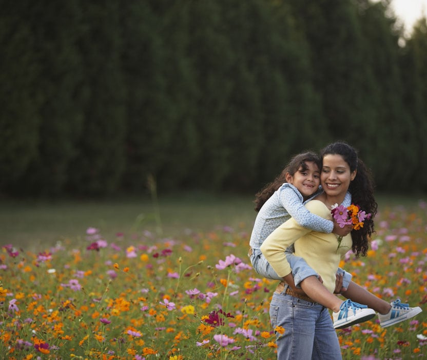 A family enjoying a sunny day in a flower field, a reminder of the importance of protecting our families from viruses.